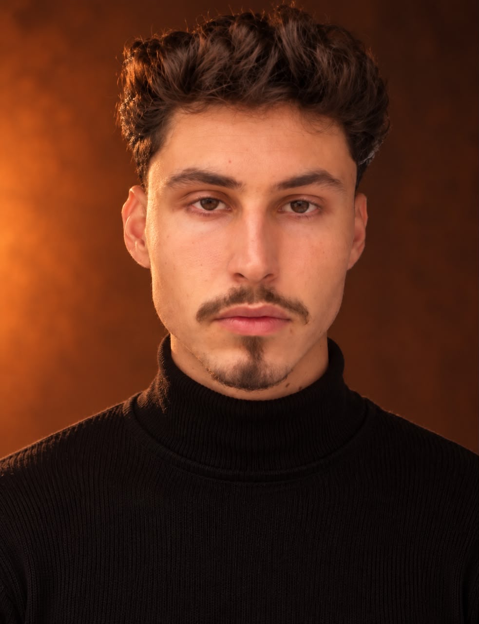 Retrato de Cristian Henrique, filmmaker e designer da Elevemente, de camisa preta de gola alta sobre fundo alaranjado